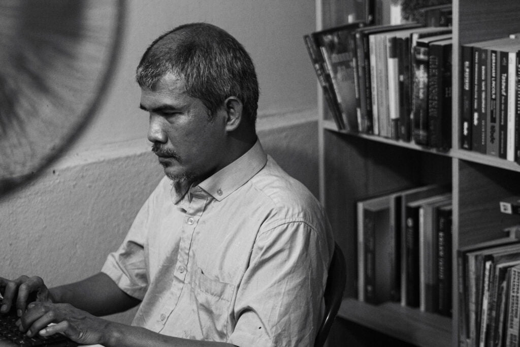 Saudara Rosli Ibrahim sedang menaip pada mesin tapi di perpustakaan peribadi di rumahnya.